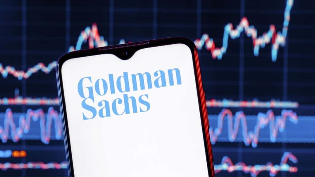 Goldman Sachs bank logo. Goldman Sachs stock chart on the background.