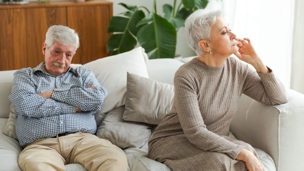 Marriage crisis relationship problems. Old couple quarreling. Sad mature disappointed woman sitting away from husband after having quarrel. Senior couple not talking having problems in relationship