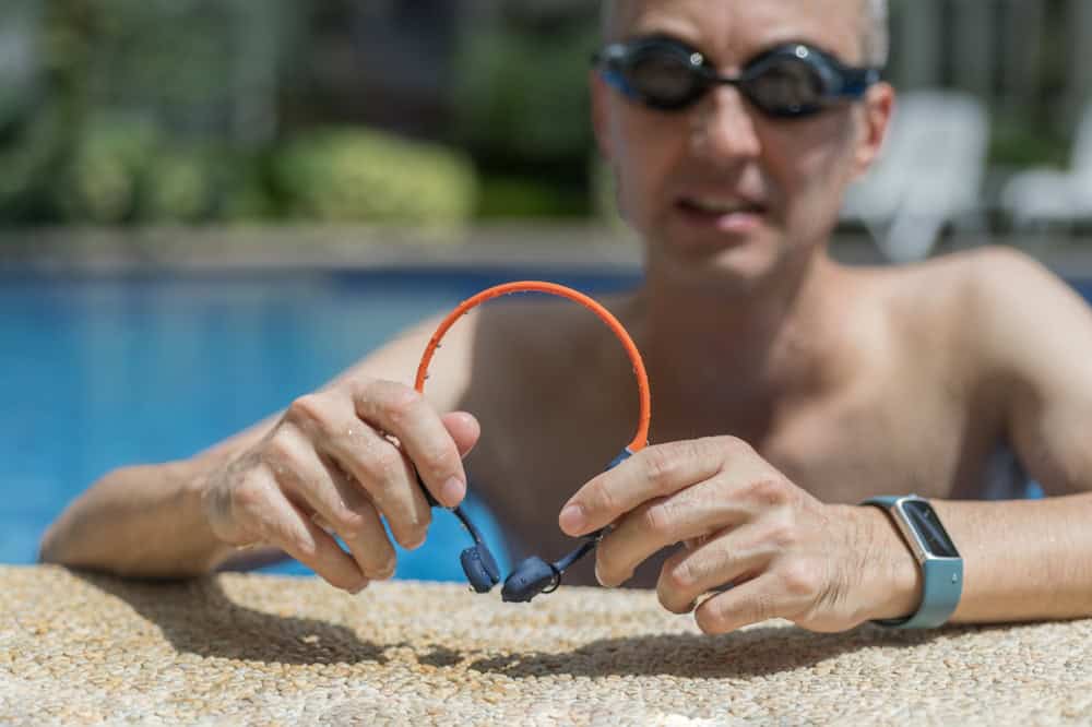 A,Man,Holds,His,Bone,Conduction,Headphones,In,Hand,,Basking