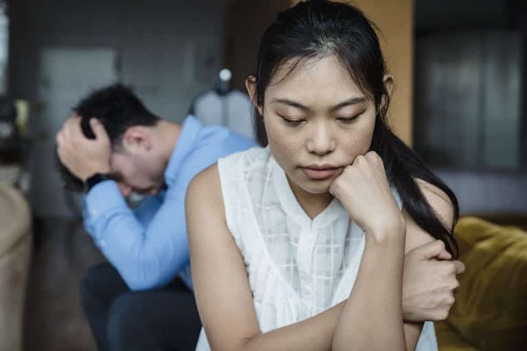 A couple experiencing relationship tension sitting silently on a sofa.