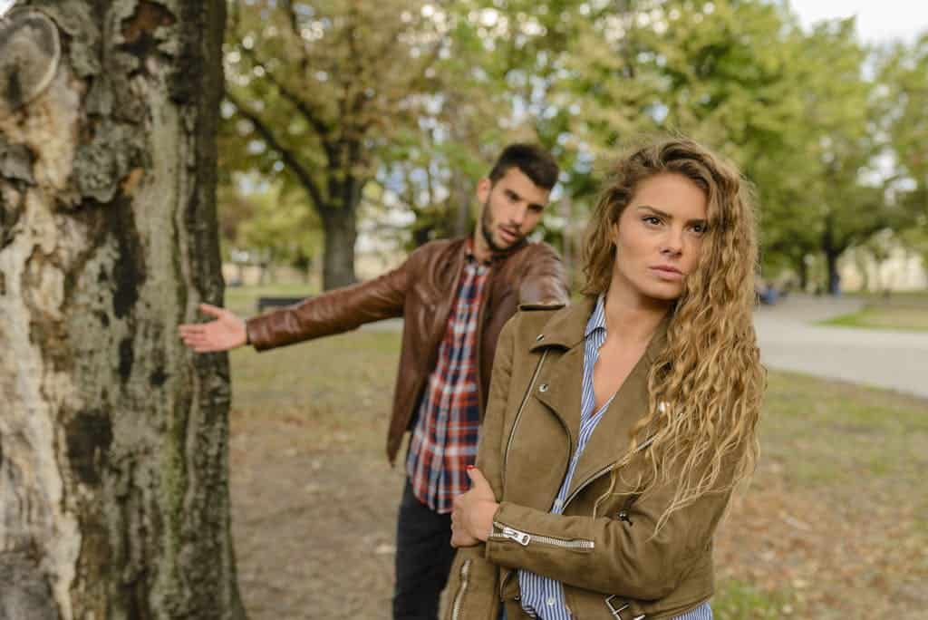 A man and woman in a heated argument outdoors, expressing emotions.