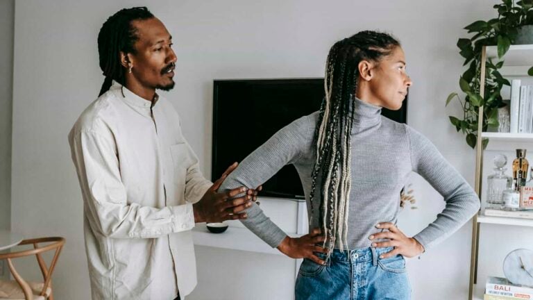 African American stylish man apologizing to sad girlfriend while having conflict at home