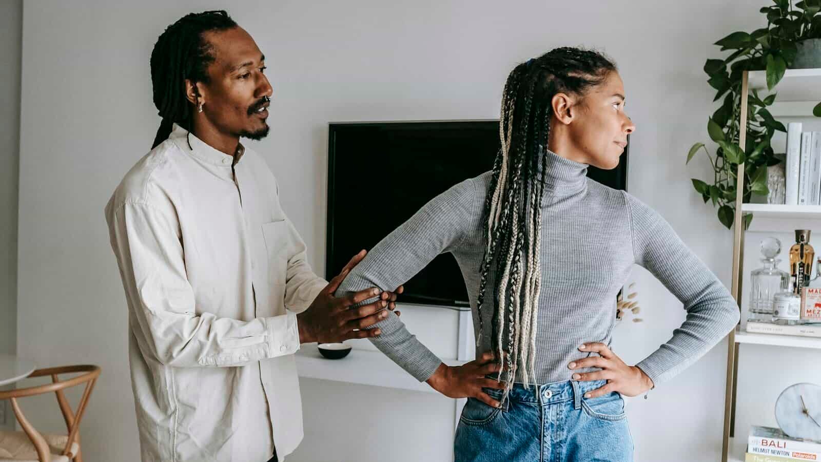 African American stylish man apologizing to sad girlfriend while having conflict at home