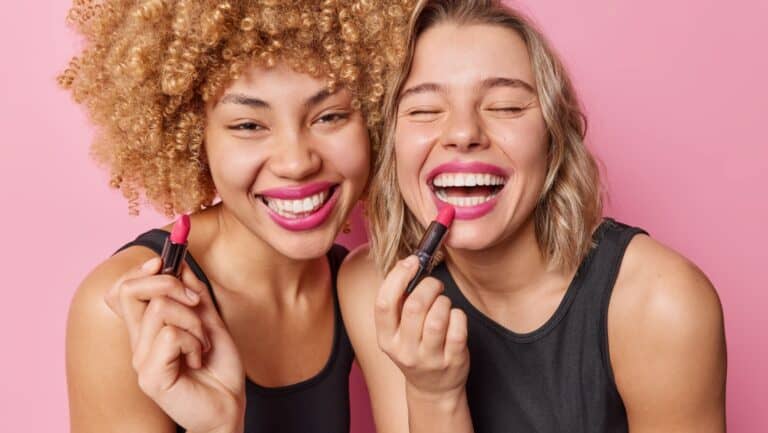 applying lipstick. Smiling women.