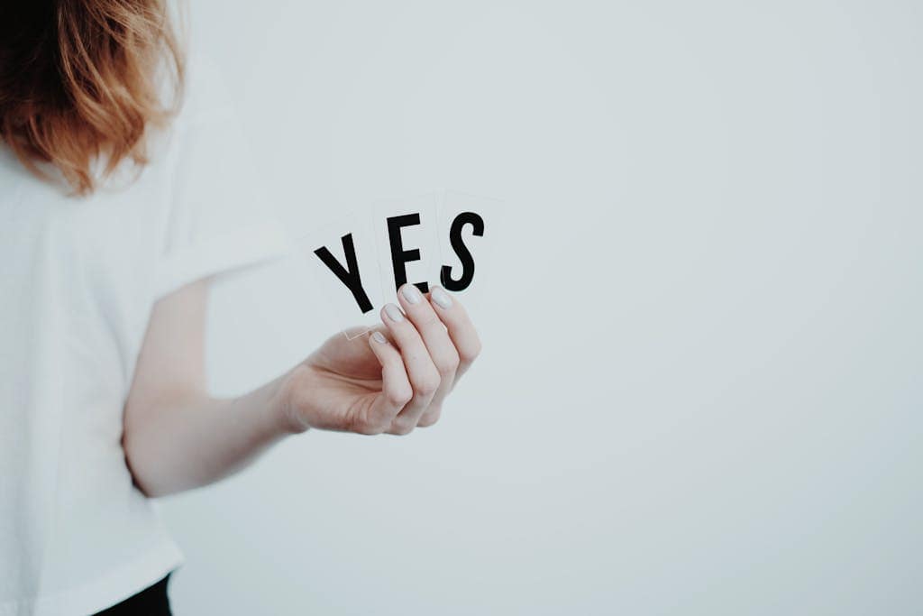 Close-up of a hand holding cards with the word 'YES' on a white background.