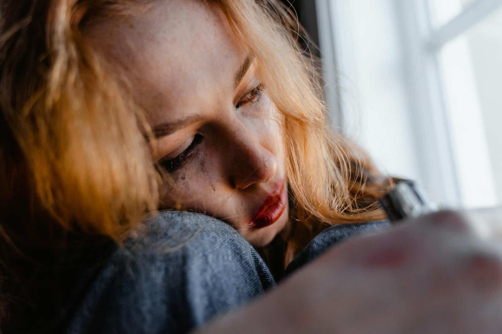 Close-up of a woman with red hair in a thoughtful and emotional moment indoors.