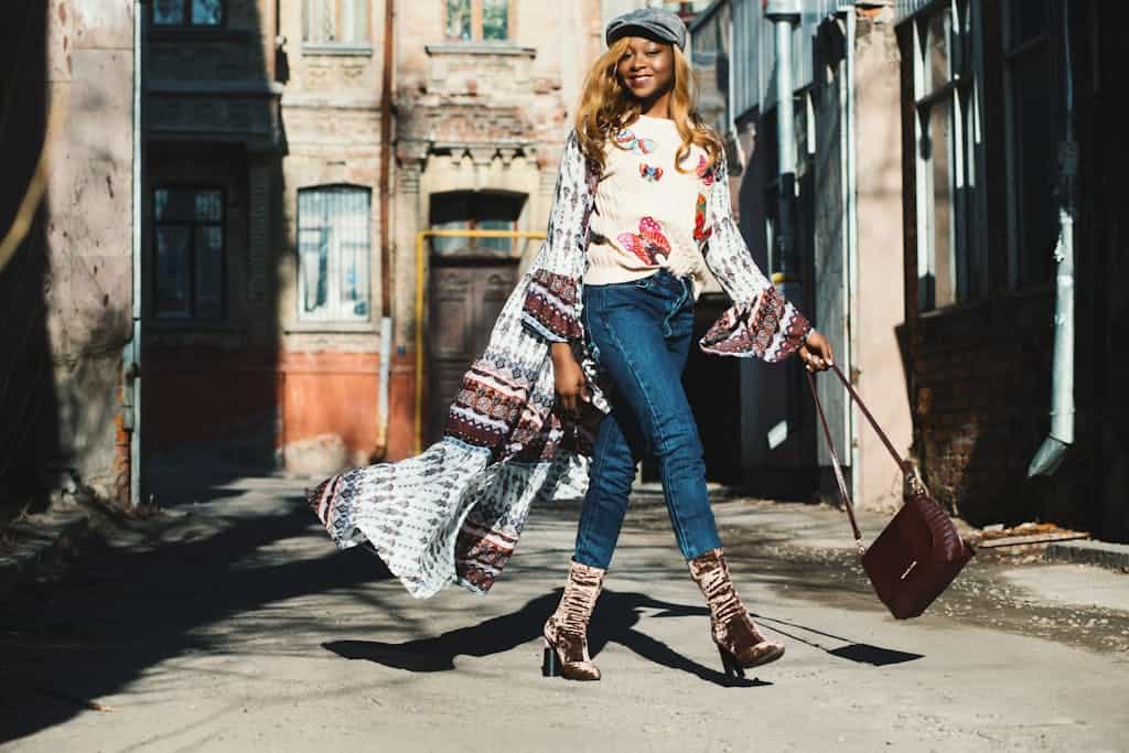 Fashionable woman striding confidently in sunlight down an urban alley, showcasing chic style.