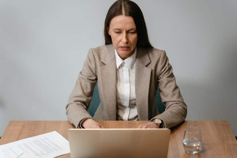 Focused businesswoman working on a laptop at her desk in an office setting.