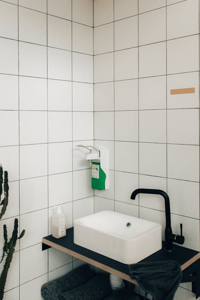 Modern bathroom showcasing sleek faucet and tiled walls in a minimalist design.