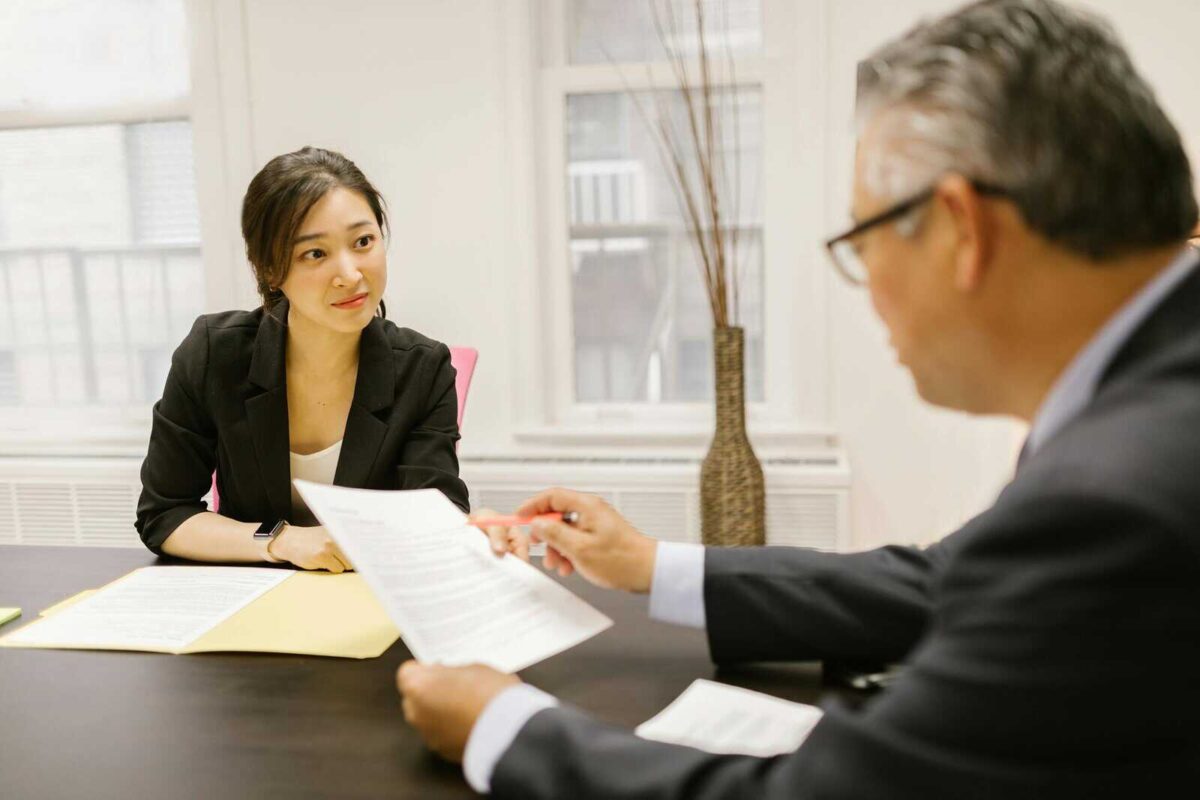 Professional colleagues discussing documents in a modern office setting. Focus on workplace collaboration and communication.