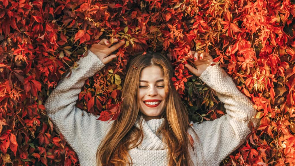 Young woman laying in Fall Leaves.