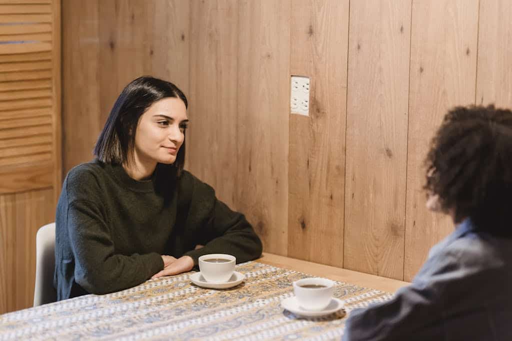 Two women enjoying a conversation over coffee in a cozy, wooden-themed café setting.