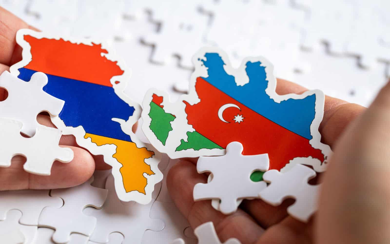 Flags of Armenia and Azerbaijan held in hands together with scattered puzzle pieces, Political puzzle concept, Difficult relations between countries, Military conflict
