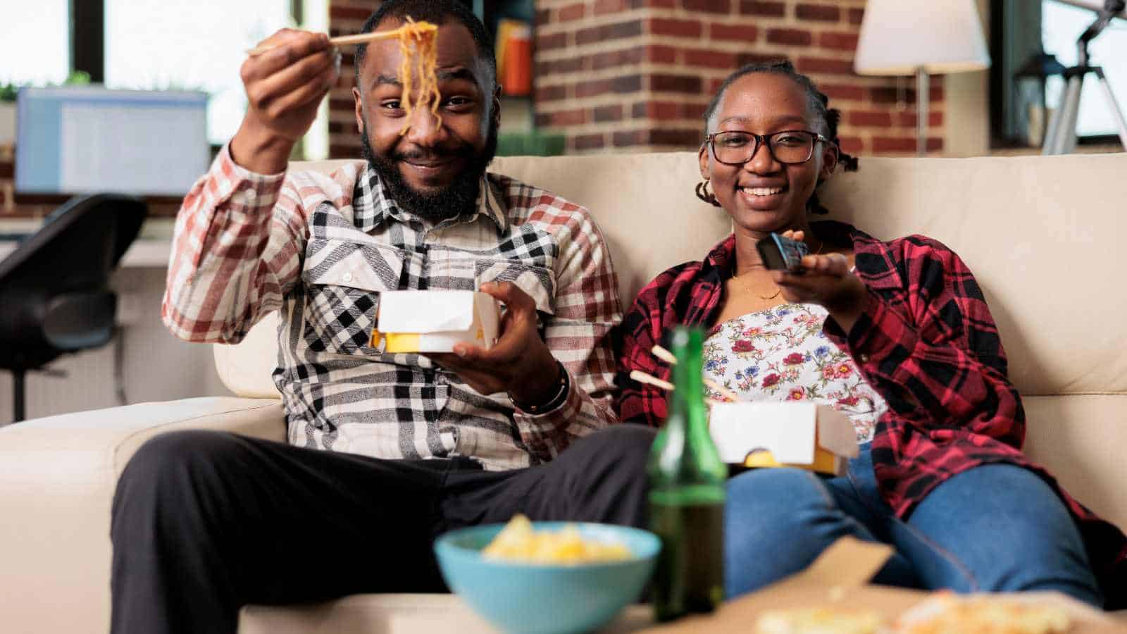 A girl and her dad having dinner while watching TV