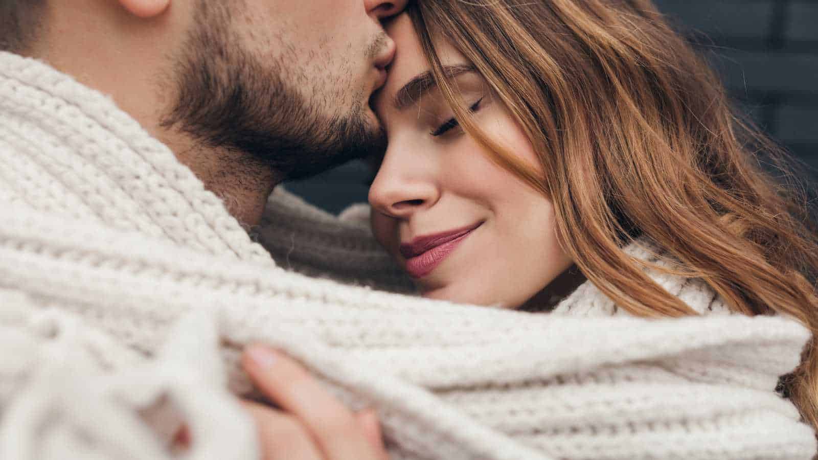 Bearded guy kissing his girlfriend's forehead