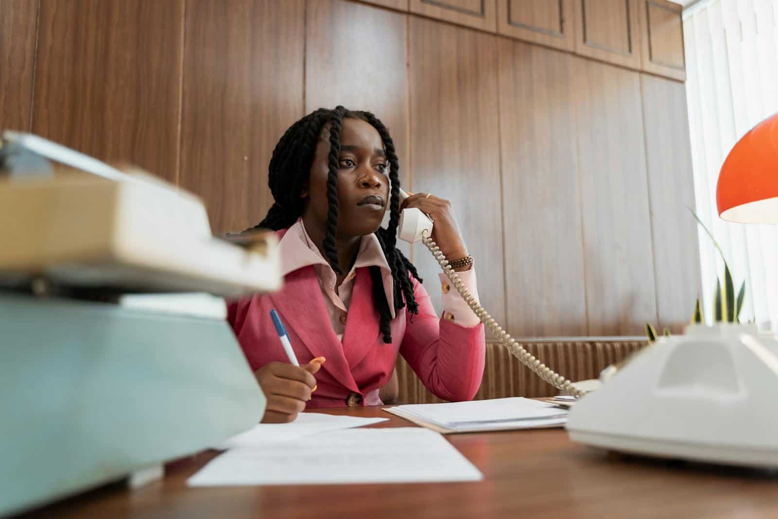 A businesswoman in vintage attire making a phone call in a retro office setting.