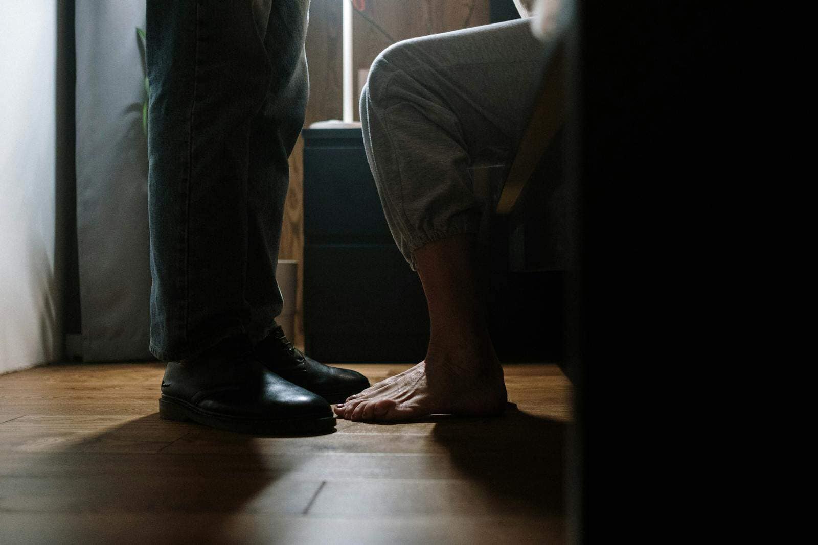 A close-up of a couple's feet indoors, depicting a warm, intimate moment.