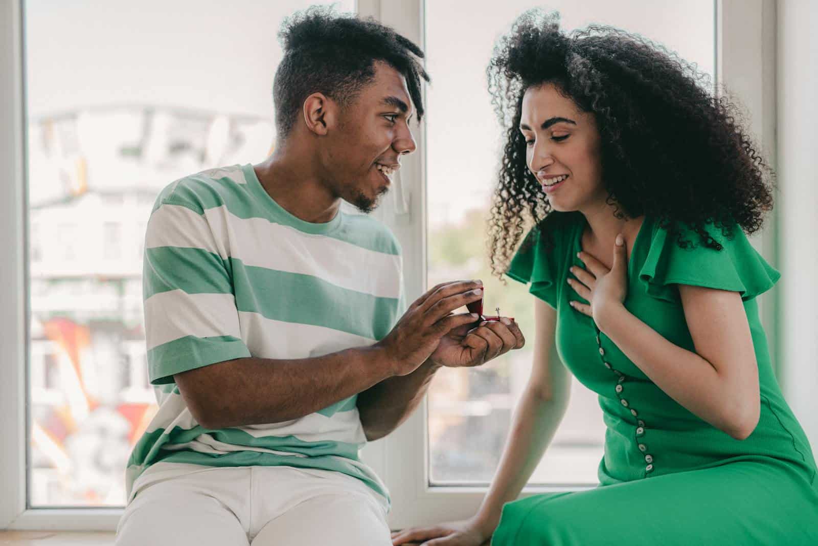 A couple in love, with curly hair, sharing a heartfelt proposal moment indoors.