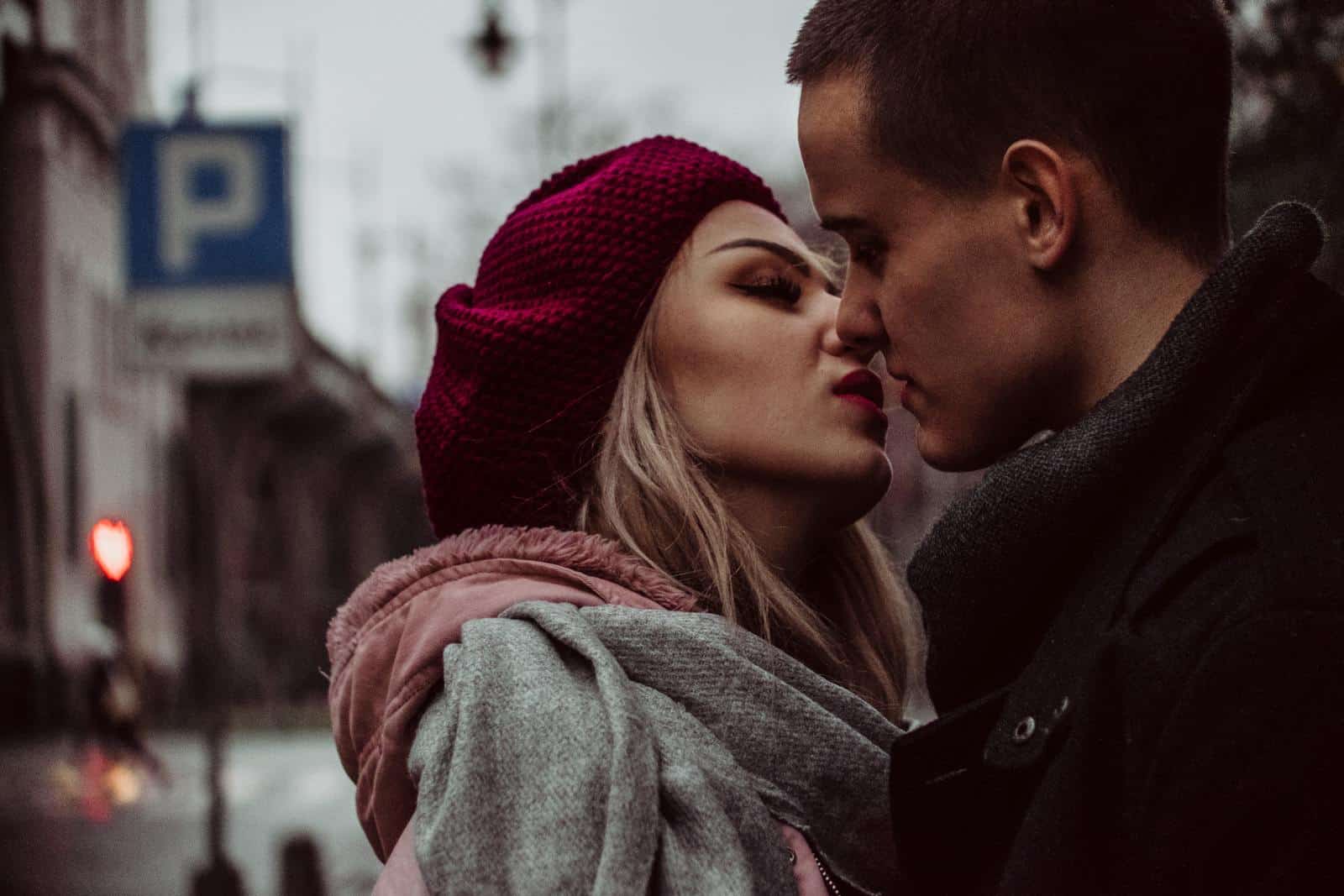 A couple shares a romantic moment in a city street during winter, capturing love and intimacy.