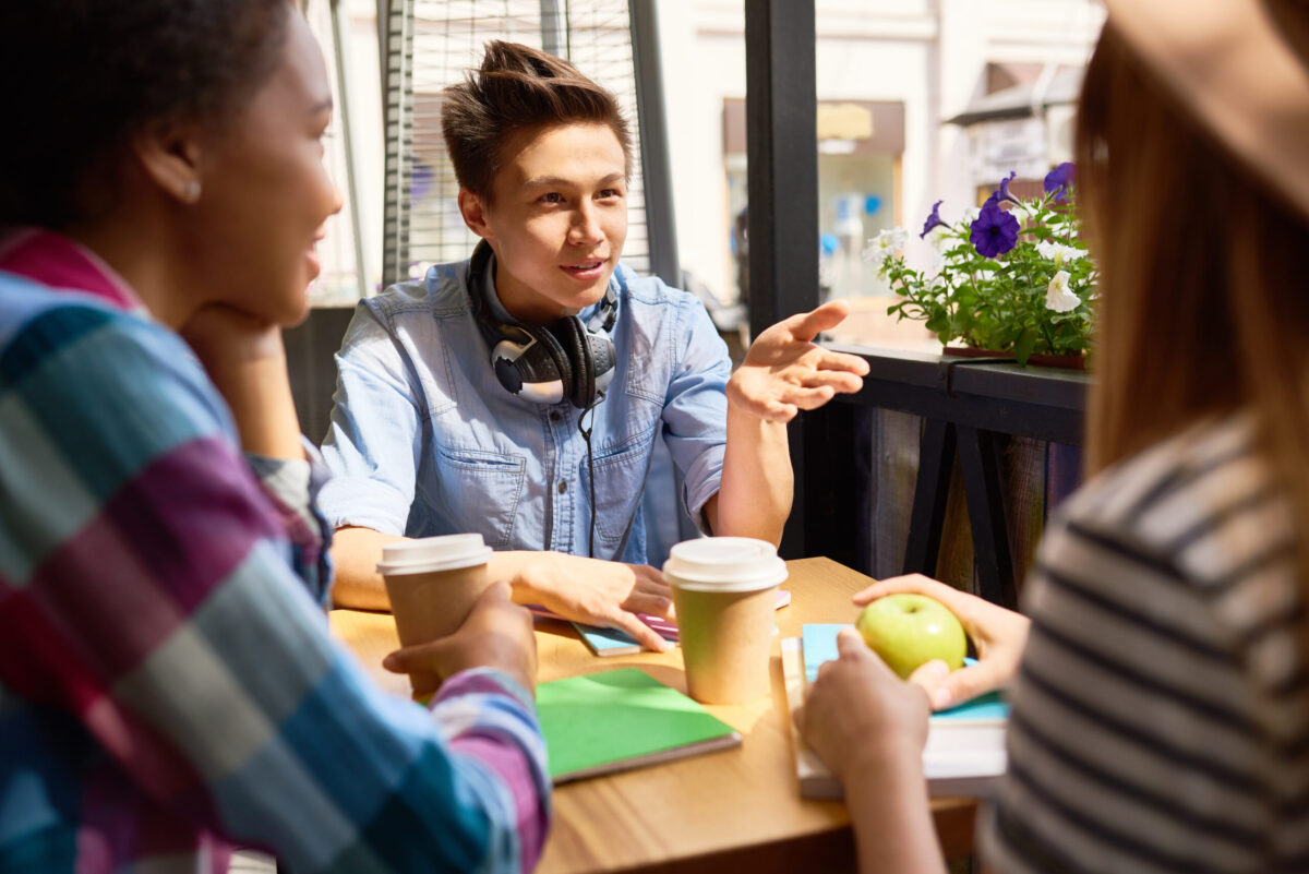 Group,Of,Three,Young,People,Chatting,Cheerfully,At,Cafe,Table