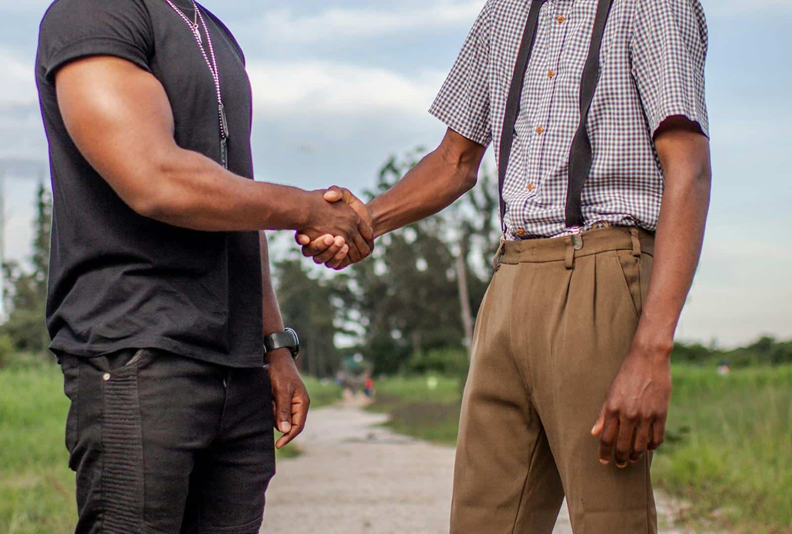 Two men shaking hands outdoors in Lusaka, Zambia. Captures cooperation and agreement.