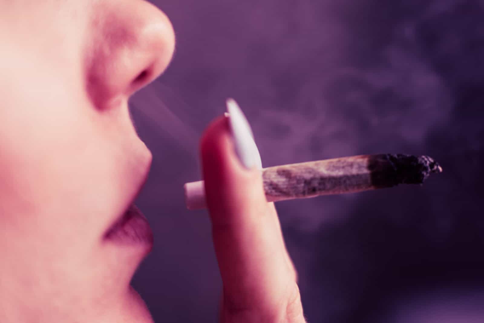 annabis weed A woman smokes, a joint and a lighter in his hands. Smoke on a black background. Concepts of medical marijuana use and legalization of the cannabis. On a black background
