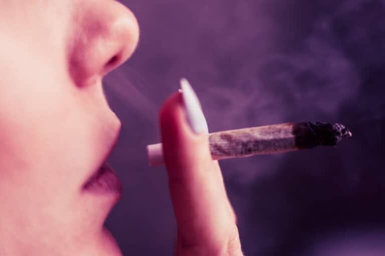 annabis weed A woman smokes, a joint and a lighter in his hands. Smoke on a black background. Concepts of medical marijuana use and legalization of the cannabis. On a black background