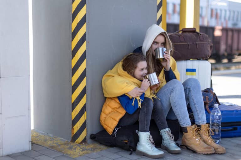 Homeless Depressed Ukrainian immigrants sitting and waiting at railway station.