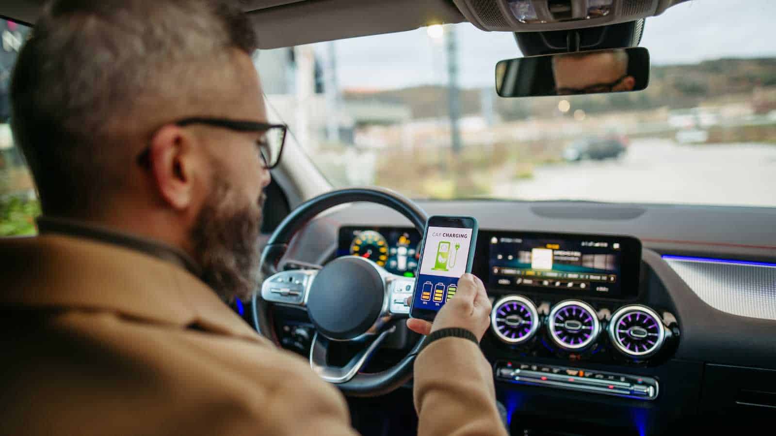 Man inside an EV checking battery status