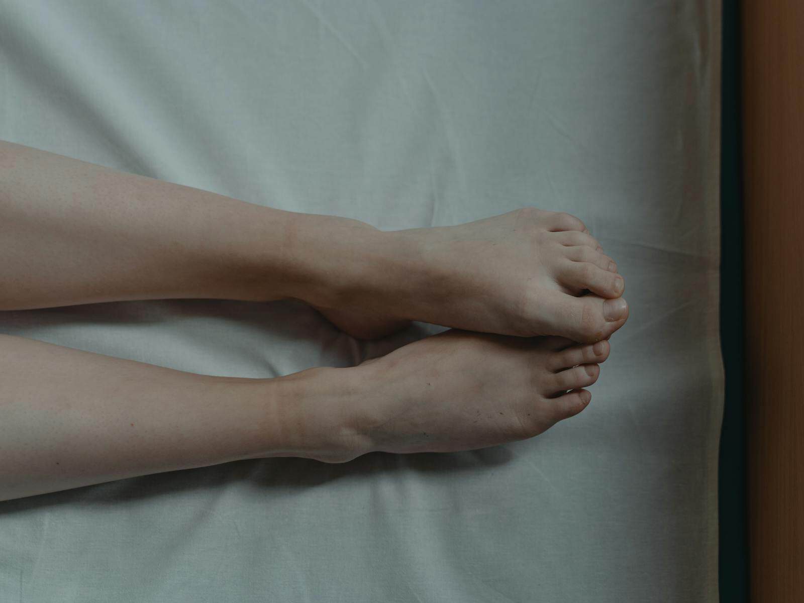 A close-up of bare feet resting on white sheets, conveying solitude and tranquility.