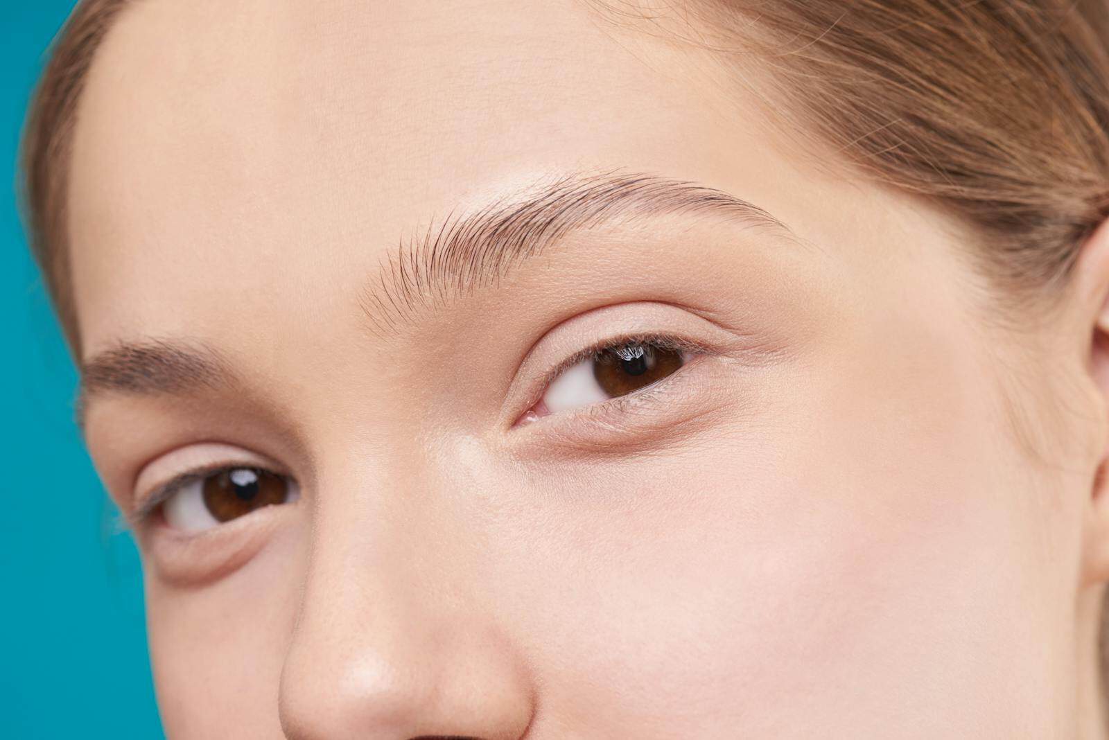 A close-up photo showcasing a woman's natural skin and eye detail, emphasizing natural beauty. Eyebrows