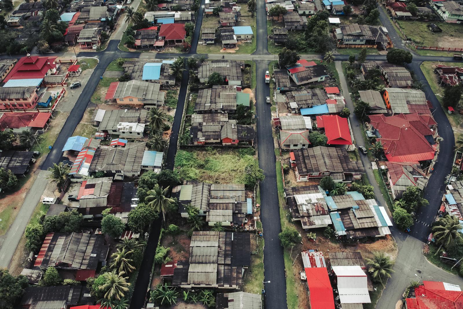 A high-angle aerial photograph showcasing residential buildings, roads, and greenery in an urban setting during the day.