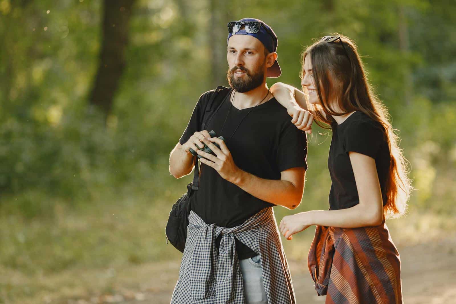 A joyful couple exploring a lush forest while enjoying the outdoors together.