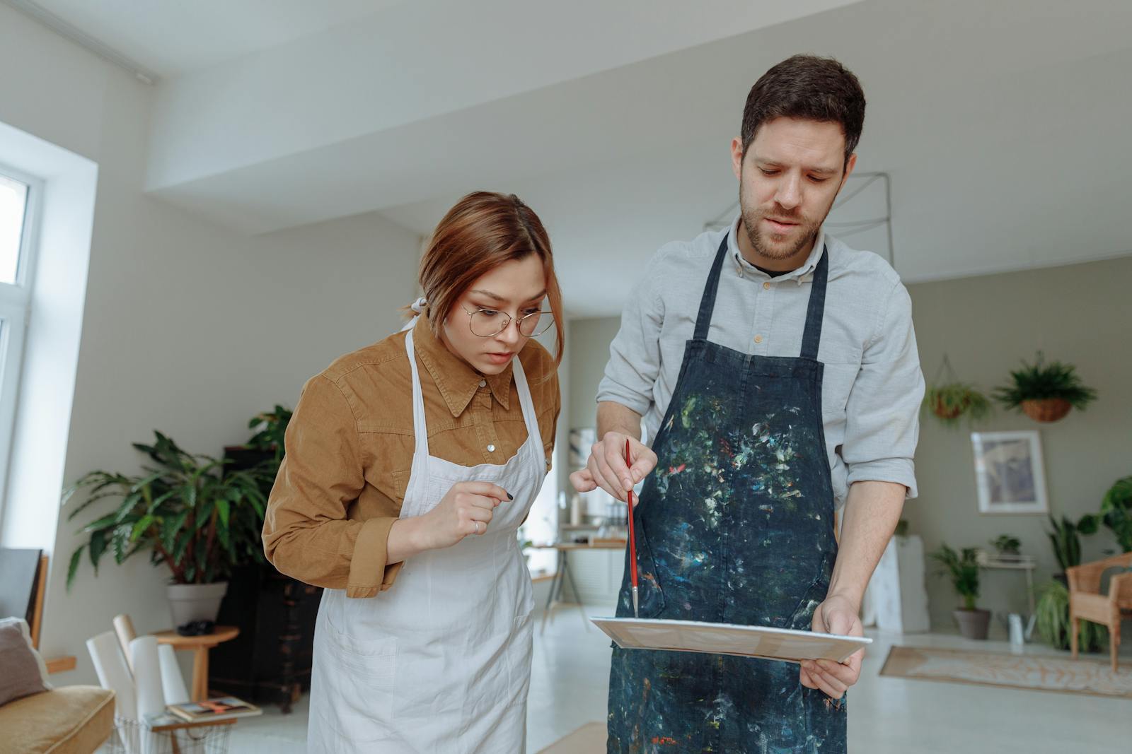A man and woman engaged in painting as a hobby in a bright, indoor studio setting.