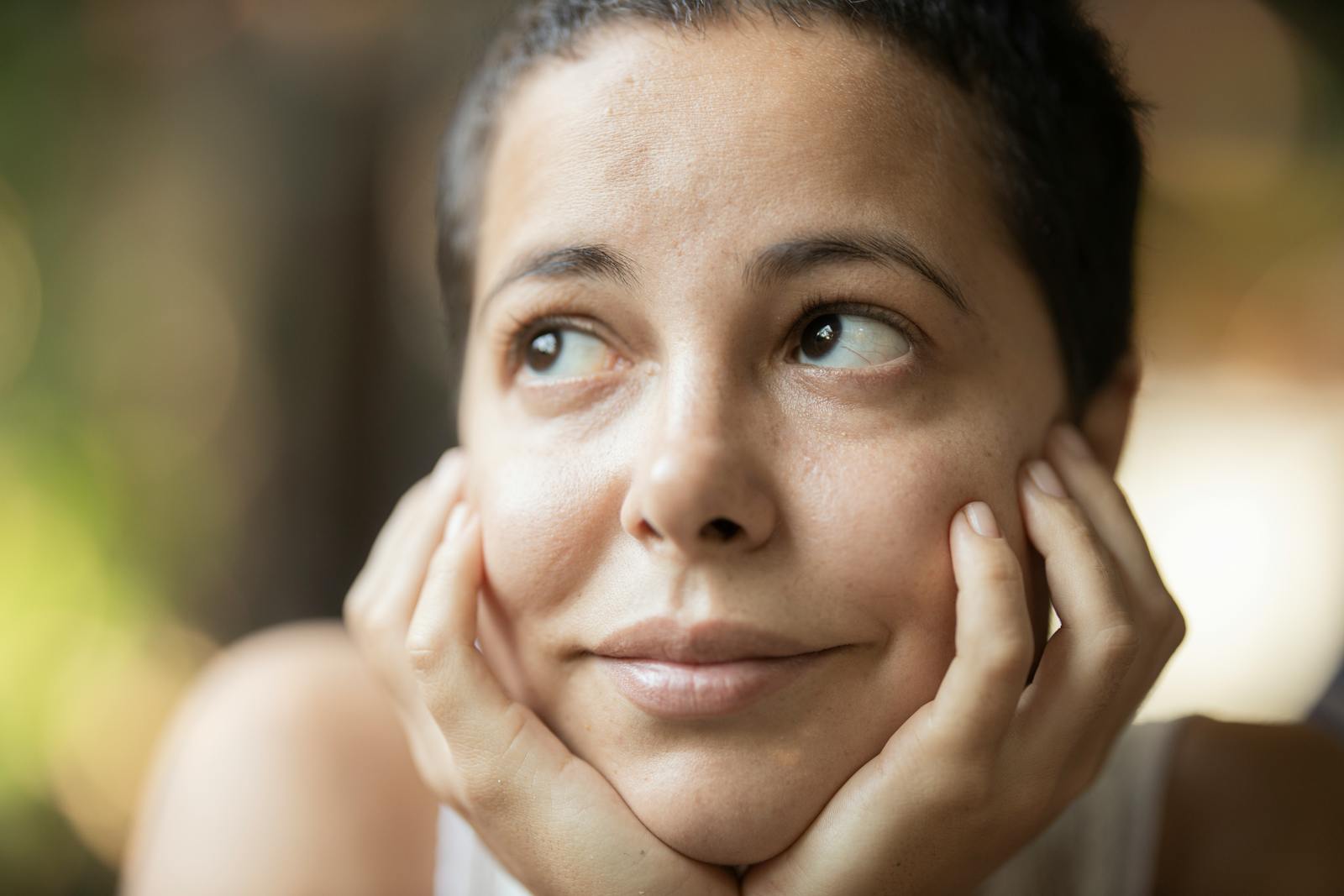 A serene portrait of a woman looking contemplatively upwards, captured outdoors with soft lighting.