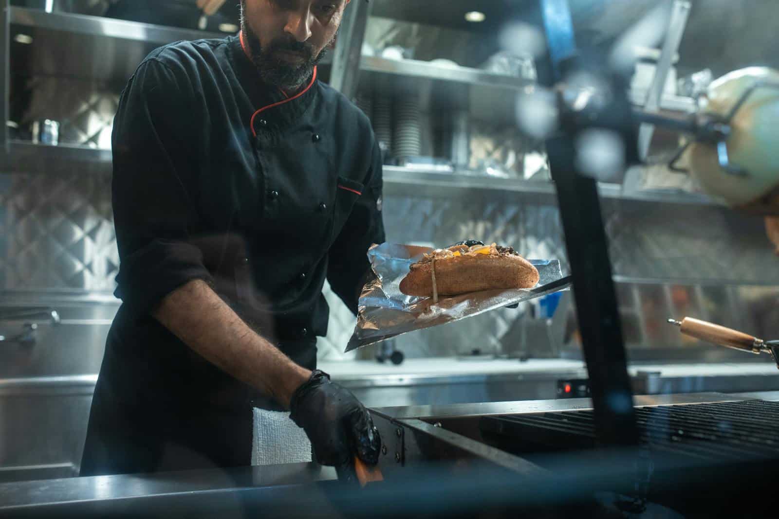 A skilled chef grills a delicious sandwich inside a sleek food truck kitchen.