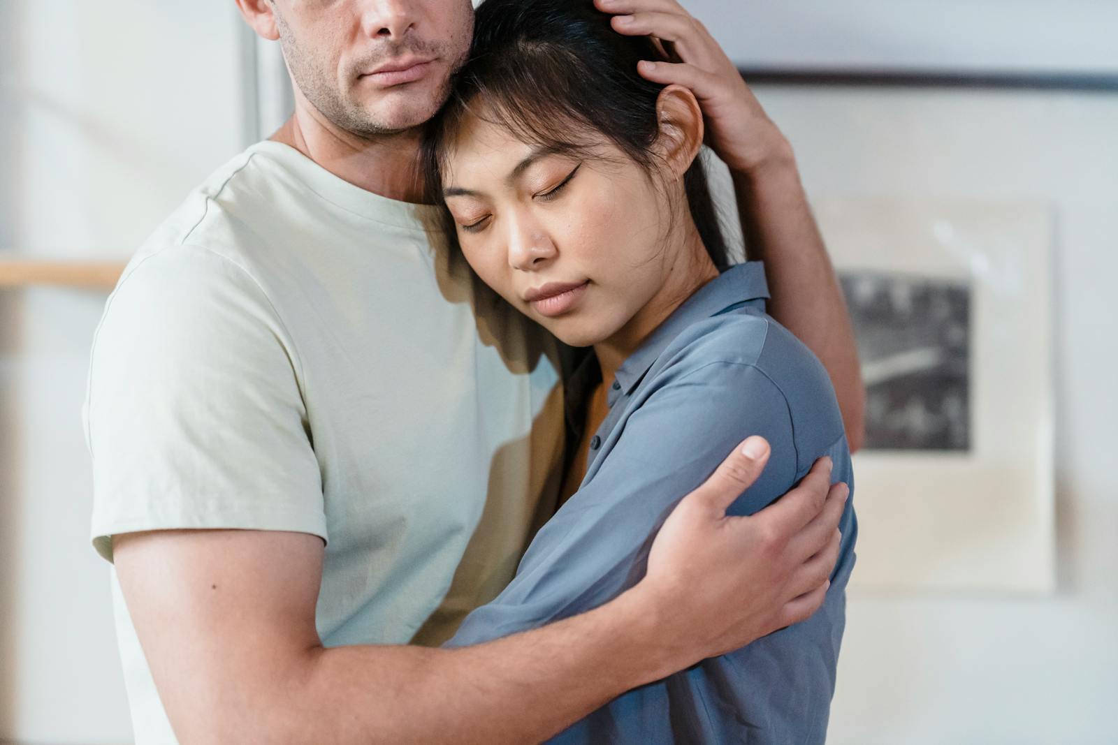 A tender moment between an interracial couple sharing a comforting embrace indoors.