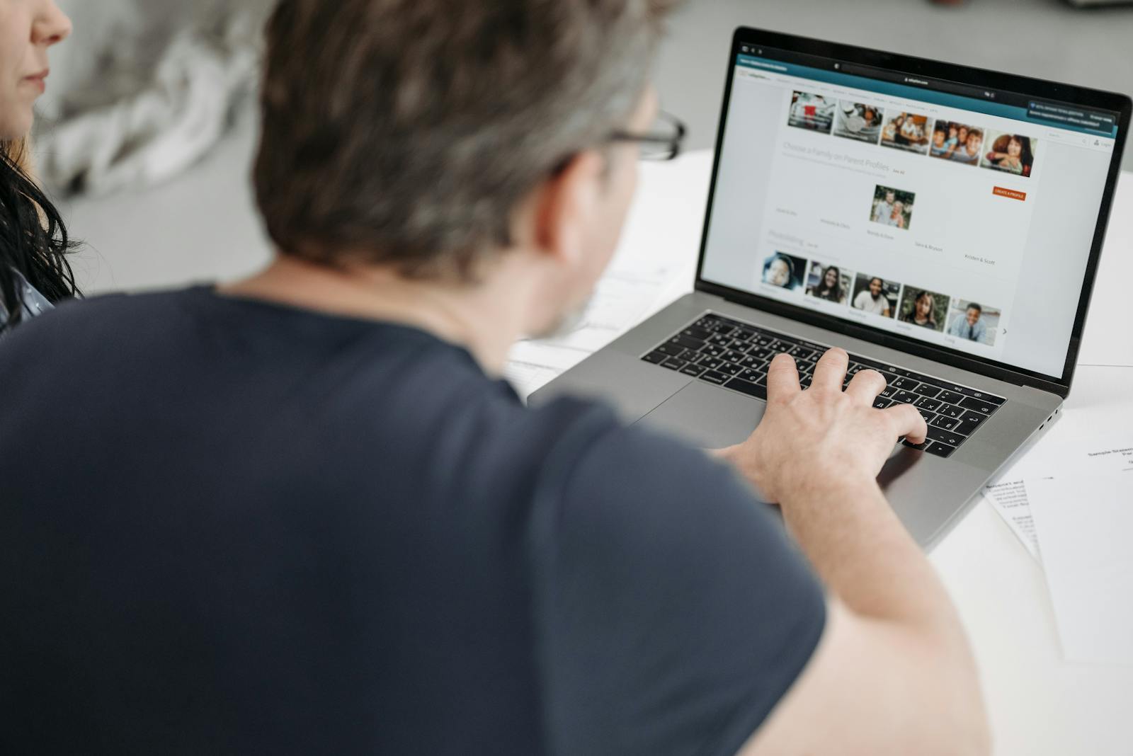 Adult male viewing online profiles on a laptop, engaged in digital browsing indoors.