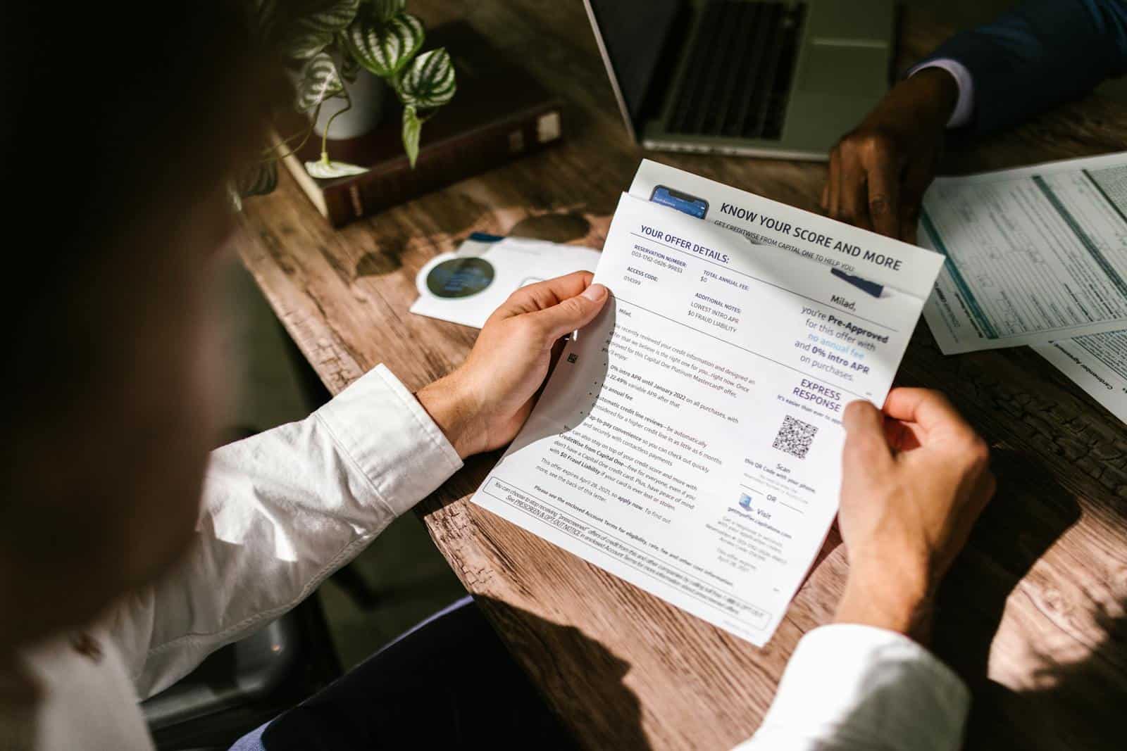 An adult man examining a financial document under natural light at a wooden desk, emphasizing finance and reading. Credit Reports