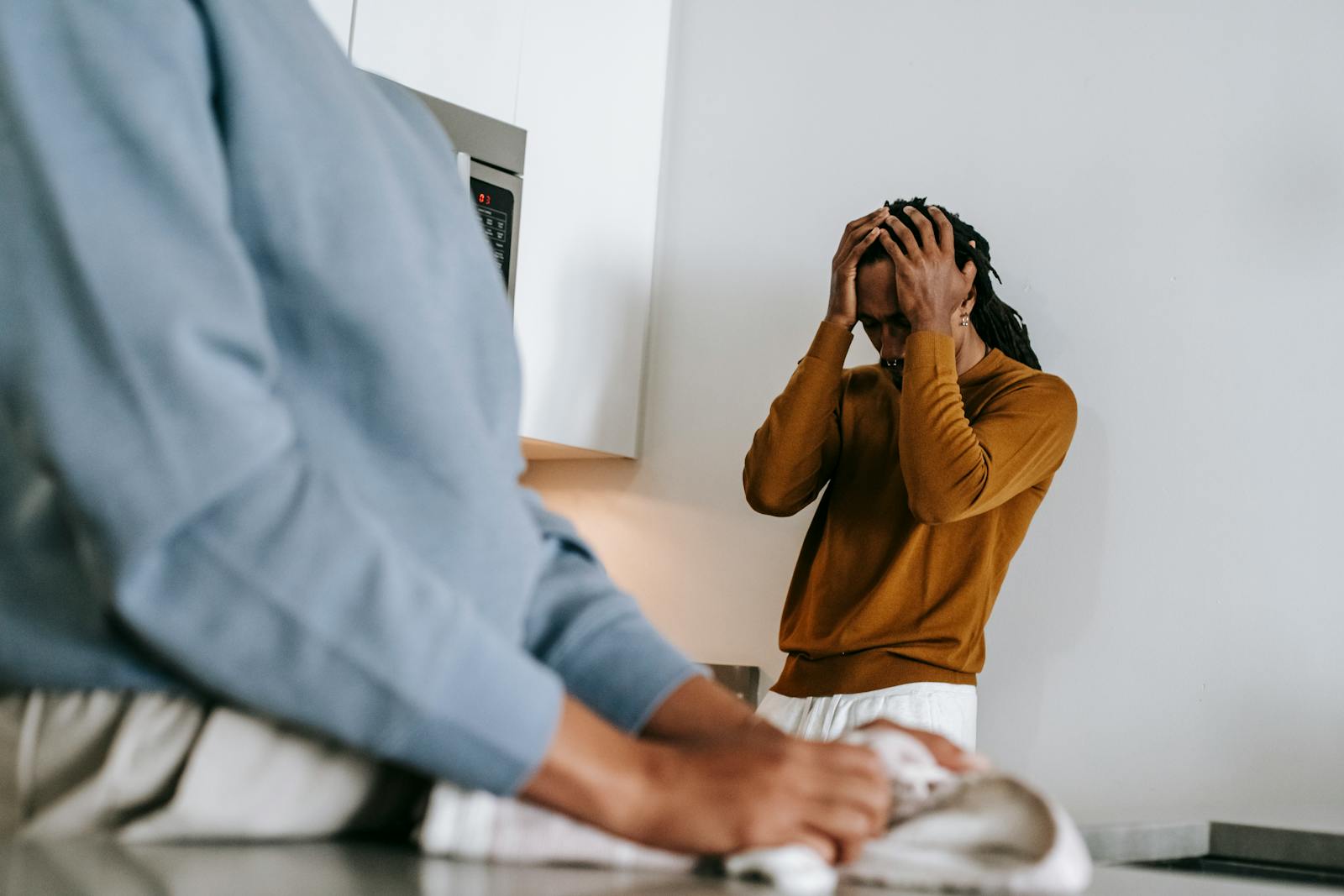 Black man and faceless woman arguing while standing in kitchen and wearing casual clothes in daytime