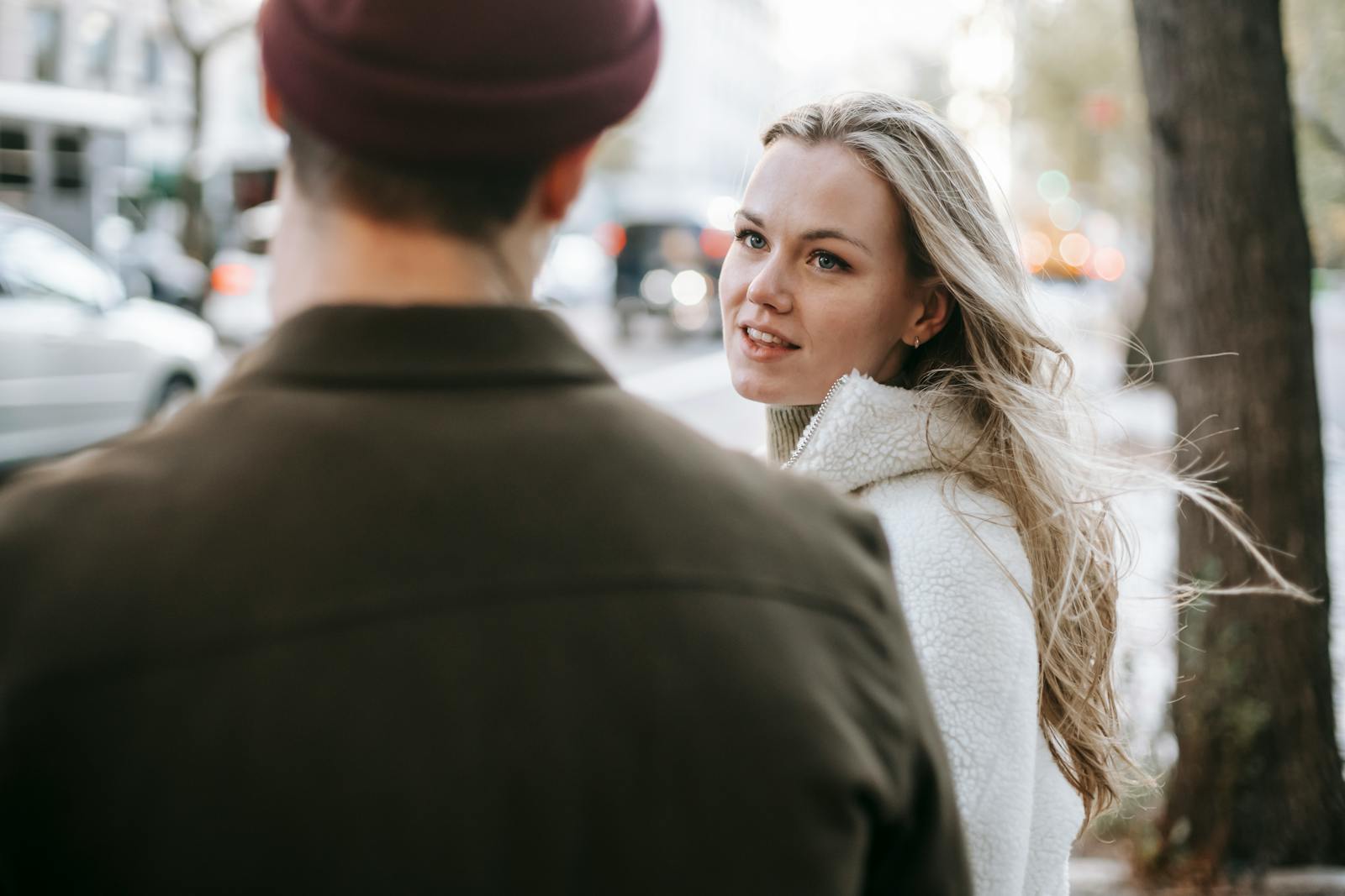 Calm couple in warm casual wear talking on city street in autumn day