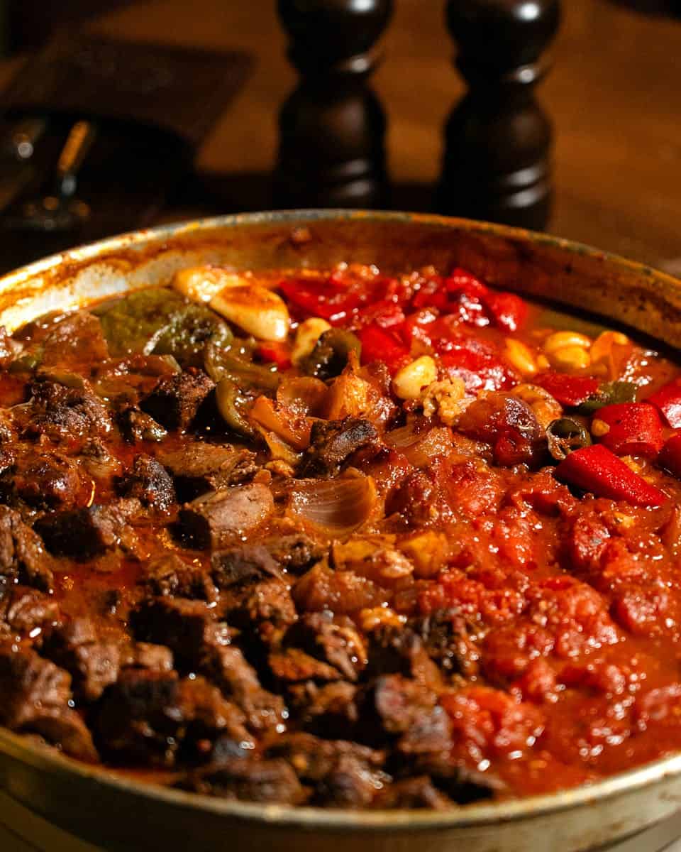 Close-up of a hearty beef stew with vibrant peppers and tomatoes, perfect for comfort food lovers.