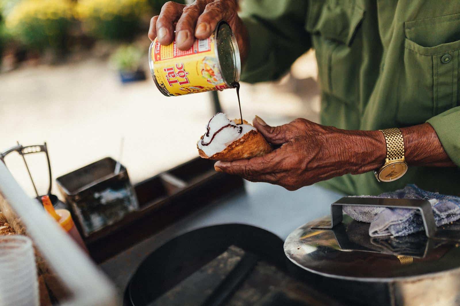 Close-up of a vendor preparing Vietnamese street food with coconut and sauce in Kon Tum. Sweetened Condensed Milk