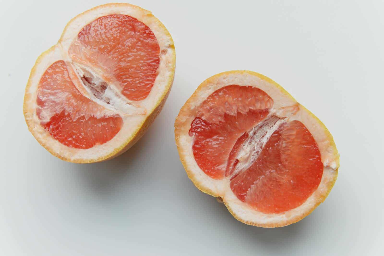 Close-up of fresh grapefruit halves against a clean white background.