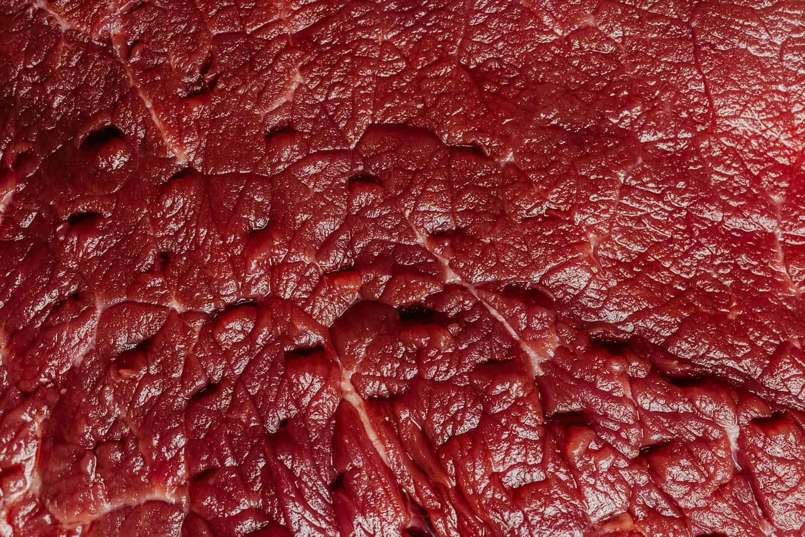 Detailed macro shot capturing the texture and marbling of raw beef meat in vivid detail.