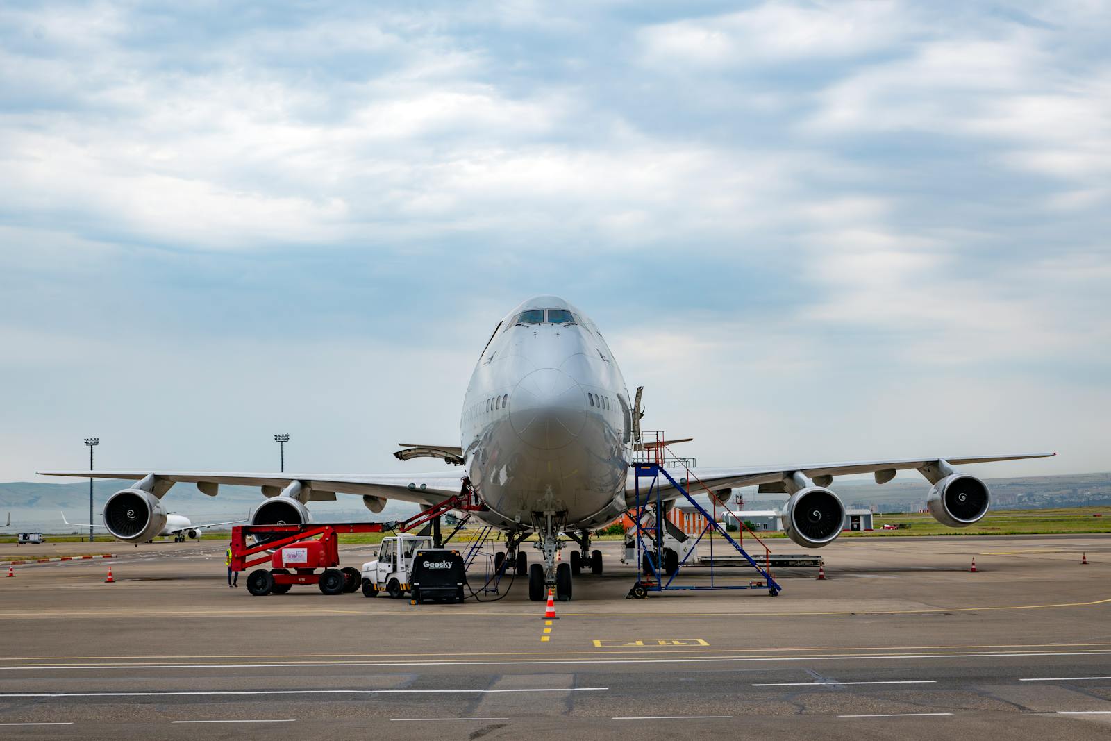Front view of a Boeing 747 airplane at Tbilisi Airport with maintenance vehicles in the foreground. Aerospace Sector