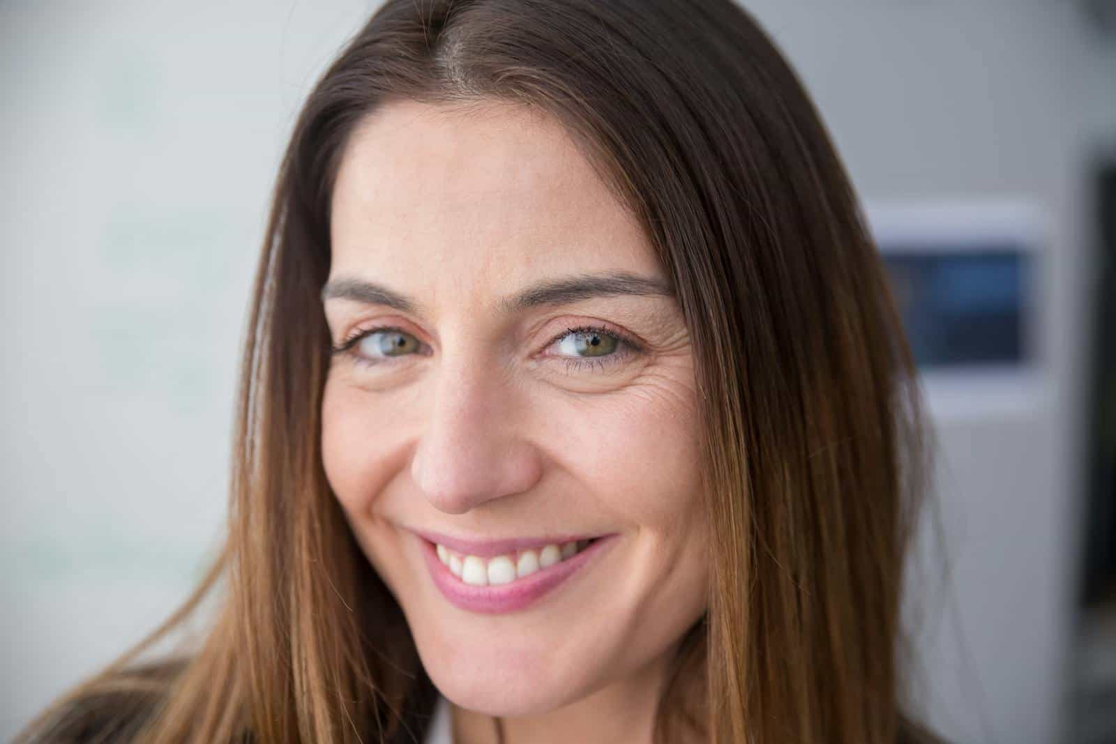 Joyful woman smiling indoors, captured in a close-up portrait. Bright and natural appearance.