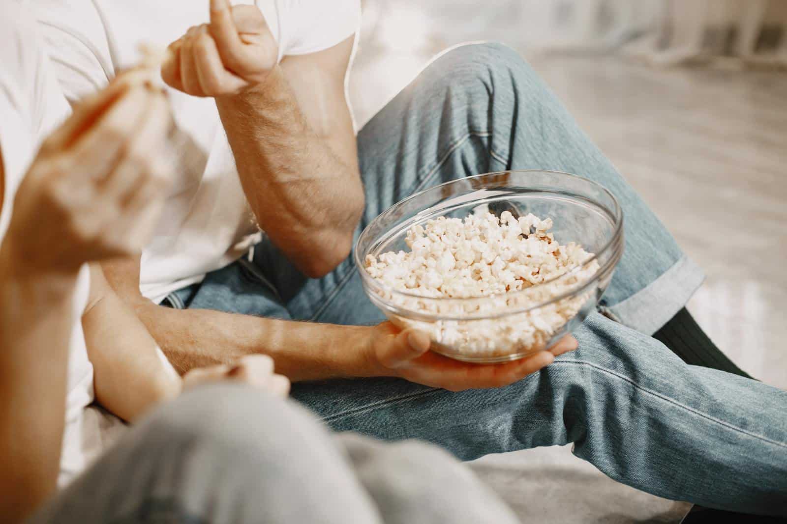 Relaxed indoor setting with people enjoying popcorn together in a glass bowl.