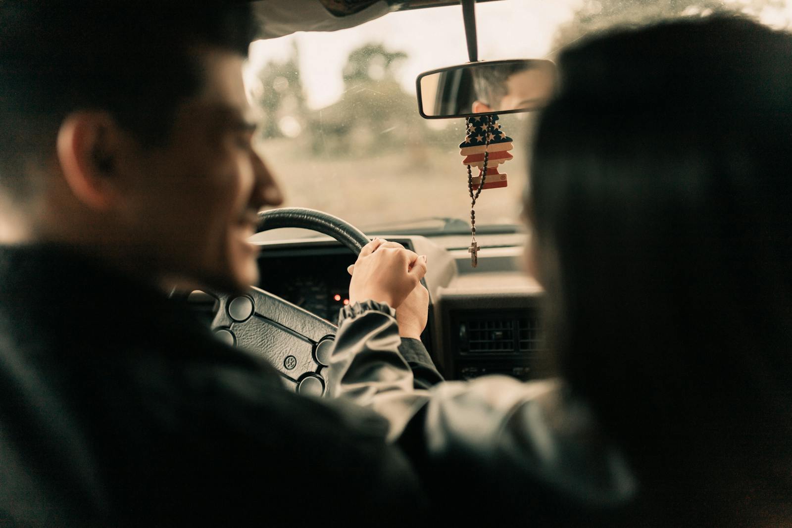 Romantic moment of a couple holding hands inside a car during a relaxed drive.