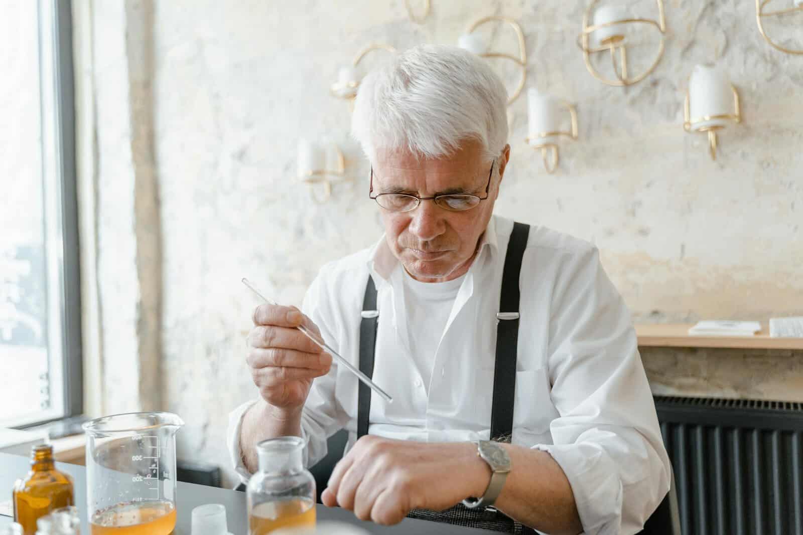 Senior man meticulously testing fragrances in a modern laboratory setting.